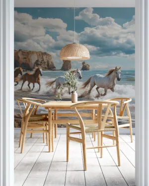 Four horses running along a scenic beach with cliffs in the background.