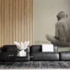 Solitary figure of an ape sitting with back turned against a light-colored background.||