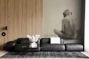 Solitary figure of an ape sitting with back turned against a light-colored background.