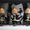 A menacing clown figure with exaggerated features|pointing a gun|set in a dark monochromatic background.